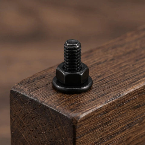 Black Furniture Connector Bolts And Barrel Nuts 40 Piece Kit For Rock Solid Bed Frame And Cupboard Assembly close-up on a bolt mounted in wood.