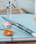 Top Shelf Premium Smooth Gel Pens That Glide Like Silk Without Skipping Or Smudging 12 Pack Of Precision 0.7Mm Black Ink Rollers on a notebook.