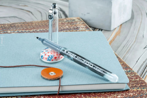 Top Shelf Premium Smooth Gel Pens That Glide Like Silk Without Skipping Or Smudging 12 Pack Of Precision 0.7Mm Black Ink Rollers on a notebook.