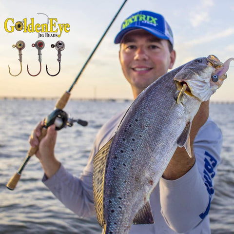 Angler holding speckled trout caught with GoldenEye One Eighth Ounce Jig Head For Inshore Fishing, visible packaging and lures.