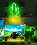 Neon cactus light decor in home gaming setup with green glow and display monitor.
