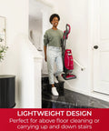 Woman using Hassle Free Bagged Upright Vacuum With No Touch Auto Dump and Smooth Lift Up Pod For Stairs on stairs for easy cleaning.