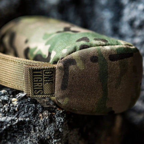 Close-up of camo Pre-Filled Shooting Rest Bag For Front And Rear Gun Support Durable 500D Cordura Nylon on rocky surface.