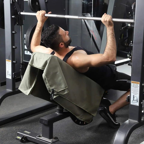 Person using gym equipment with ultra compact microfiber towel for travel, gym, and camping draped over bench