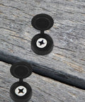 Zero Hassle 100 Piece Hinged Screw Cover Set In Durable Black Plastic Engineered For Medium Fasteners on wooden surface.