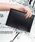 Hand holding Black Waterproof Bubble Mailers 4x8 Self Seal Adhesive Shipping Bags, 200 Pack Cushioned Padded Envelopes