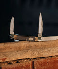 Solid As A Rock Pocket Folder With 2 Inch Clip Point Blade Crafted From High Carbon Stainless Steel And Rough Cut Sawcut Grip on log