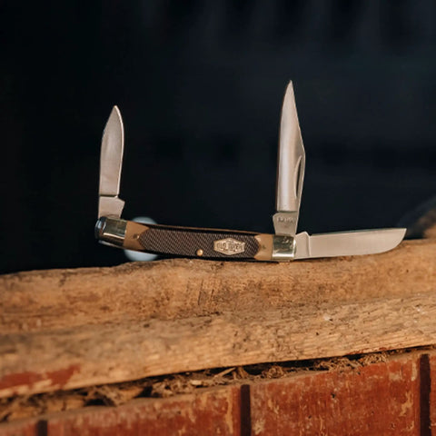 Solid As A Rock Pocket Folder With 2 Inch Clip Point Blade Crafted From High Carbon Stainless Steel And Rough Cut Sawcut Grip on log