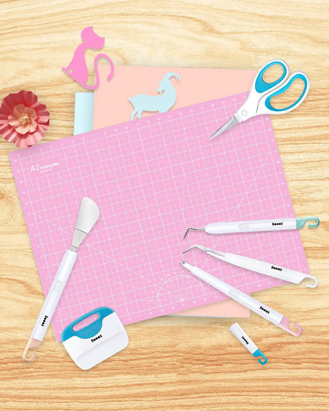 Six Piece Vinyl Tool Kit For DIY Crafters With Scoring Stylus Weeder With Cap Scissors Tweezers Spatula And Scraper displayed on pink mat
