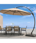 Outdoor scene with 11 Ft Deluxe Cantilever Outdoor Umbrella With Base Included Heavy Duty Rotating Offset Patio All Weather Shade over a patio table.