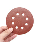Hand holding a disc from 35 Piece 5 Inch Sanding Discs Set With 8 Hole Pattern Hook And Loop, 7 Grits 60 80 100 120 150 180 240 For Random Orbital Sander