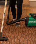 Lightweight Portable Canister Vacuum Delivering Beefy Suction And Dead Quiet Operation For Rough Daily Work Includes Eight Piece Tool Kit To Bust Through Grime Without The Headache Smooth Handling In Green And Black on a carpet.