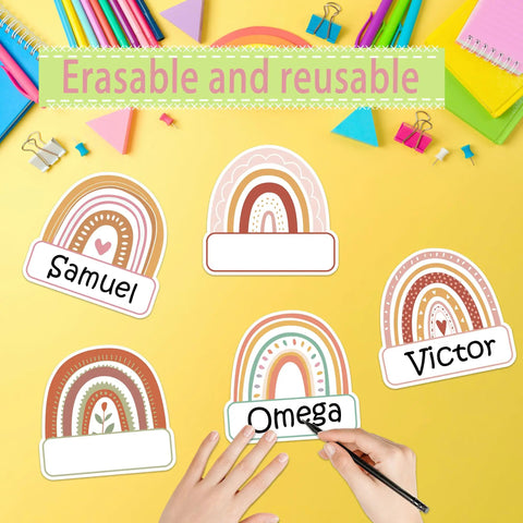 Rainbow Cutouts For Classroom Decor, 45 Pcs Boho Rainbow Name Tags With 100 Glue Dots on yellow desk with hands writing names