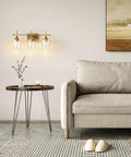 Three Light Vanity Light With Clear Glass Shades In Modern Gold Finish For Bathroom Over Mirror Contemporary Wall Lamp For Soft Balanced Lighting In Bathroom Bedroom Or Hallway mounted on wall beside sofa and table.