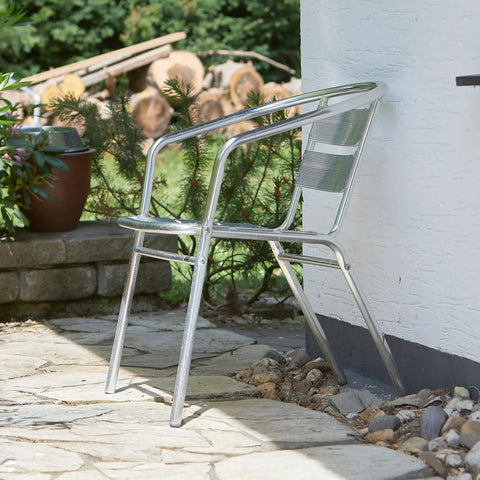 Aluminum chair placed on patio near brick wall and potted plants, showing outdoor setting.