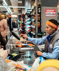 Store cashier assisting customers with a 'Sorry No Public Restrooms' sign in background, Two Pack No Public Restroom Signs For Biz And Home Self Adhesive Weatherproof Vinyl Stickers For Office Window And Door No Public Bathroom Sign Durable Frosted Vinyl With Heavy Duty Backing visible.
