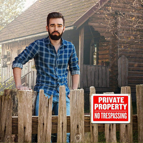 Man standing by a wooden fence with a Private Property No Trespassing sign 9x12 inches weatherproof and water resistant displayed.