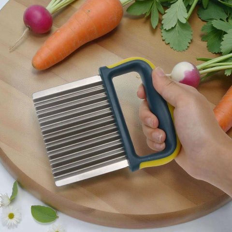 Crinkle cutter knife with stainless steel ridged blade and blue-yellow handle held over a wooden cutting board with carrots and radishes