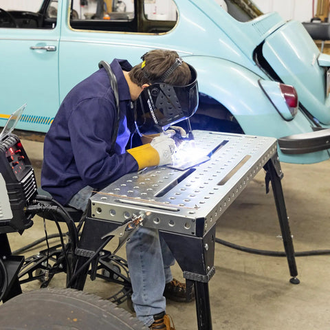 Person welding at Built Rugged Foldable Welding And Fixturing Table Packing 500 Pound Capacity And Industry Standard Holes.