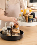 Person using Non Slip Rotating Lazy Susan Turntable 360 Degree Swivel With Grippy Textured Surface Black 10 Inch on kitchen table.