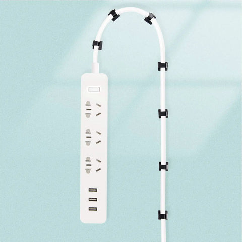 50 Pack Peel And Stick Self Adhesive Cable Clips And Wire Organizers For TV PC Laptop Ethernet Cables Sticky Cord Holders neatly securing a white power strip cable against a light blue background.