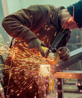 Image of a worker using an Ergonomic Side Handle for Angle Grinders with a Grip That Holds like Glue in a workshop.