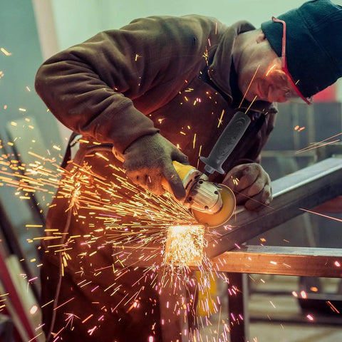 Image of a worker using an Ergonomic Side Handle for Angle Grinders with a Grip That Holds like Glue in a workshop.