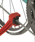 Grunge Brush Bike Chain And Gear Cleaner With Dual Sided Bristles cleaning bike chain and cassette, attached to rear wheel.