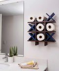 Tic Tac Toe Toilet Paper Holder Dope Wall Mounted Storage for Bathroom Decor with blue X's and toilet paper rolls over sink.
