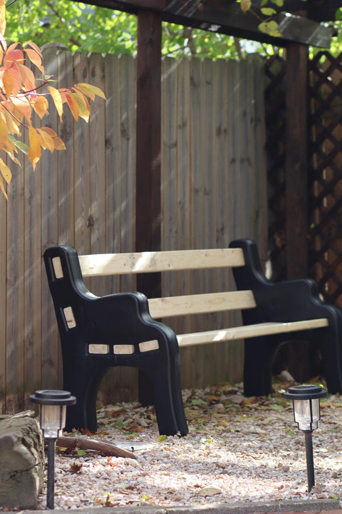 DIY Bench Ends Kit For Outdoor And Patio Benches in garden scene, black resin ends with 2x4s under a pergola, no hardware