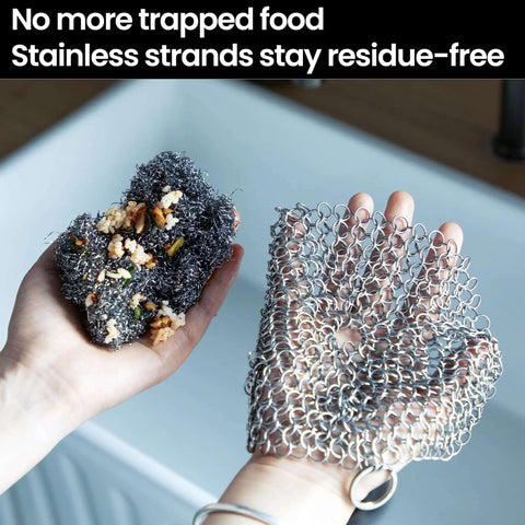 Hands holding cast iron scrubber with stainless steel chainmail next to a soiled sponge in a kitchen sink, showcasing its residue-free properties.