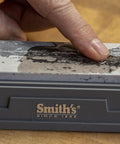 Close-up of a finger applying Honing Oil For Sharpening Stones 4oz Bottle Keeps Tools And Knives Slick to a sharpening stone surface.