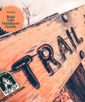 A wooden trail sign outdoors with Boss Life Outdoors Guide badge