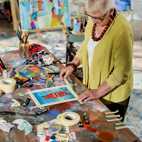 Woman using Six Roll Masking Tape Pack 0.75 Inch By 60 Yards Multi Surface Paper Tape for painting on an art table.
