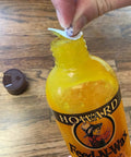 Person peeling seal off orange scent wood polish and conditioner cream formula with natural oils, bottle on wood floor.
