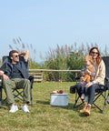 People sitting in Oversized Folding Camping Chair For Outdoors, Built Tough Heavy Duty Quad Lawn Chair With Side Pockets in a grassy area.