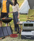 Outdoor setup with Plug And Play Solar Panel Extension Cable 20FT 14AWG, connecting power station beside grill and tent.