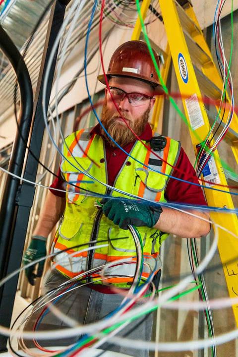 Electrician handling heavy duty building wire stranded copper 12 gauge 1 conductor 20 amp on job site with ladder and equipment.