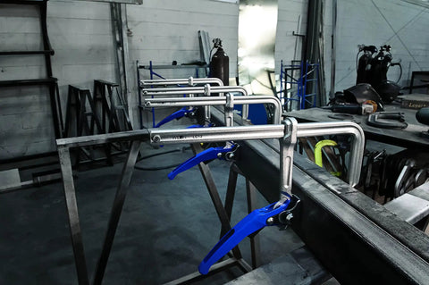 Heavy Duty Top Shelf 12 Inch Lever Clamp Packing 1100 Pounds Of Iron Grip Hold With Spindle Free Ratcheting Action And Ergonomic Handle For Fast Track Shop Projects, multiple clamps on a metal frame.