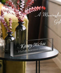 Custom Engraved Desk Name Plate In Acrylic on table with flowers, personalized for Human Resources Director, modern office decor.