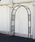 Powder Coated Iron Garden Pergola Arbor Built For Climbing Plants in front of a white wall, featuring decorative trellis design