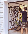 Beefy Four Bike Wall Mount Storage Rack Built From Solid Steel With Heavy Duty Garage Grade Construction Holds Up To 200 Lbs Across Four Bikes With Rubber Coated Hooks For Easy Access installed in garage with bikes.