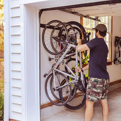Beefy Four Bike Wall Mount Storage Rack Built From Solid Steel With Heavy Duty Garage Grade Construction Holds Up To 200 Lbs Across Four Bikes With Rubber Coated Hooks For Easy Access installed in garage with bikes.