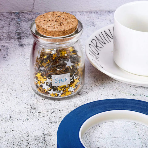 Blue 1/2 Inch Painter Drafting Tape For Crafting And Masking, 55 Yards Long near a jar of stars and a cup on a textured surface