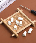 Front view of white ceramic wire connectors (porcelain caps) on a small bamboo tray with a screwdriver.