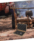 Rugged Survival Storage Box With Shockproof Organizer for outdoor tools next to camping fire, open, showcasing compartments.