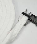 Close-up of white Lynn Manufacturing ceramic fiber strip blanket measured with caliper; 1 in wide, 1/2 in thick