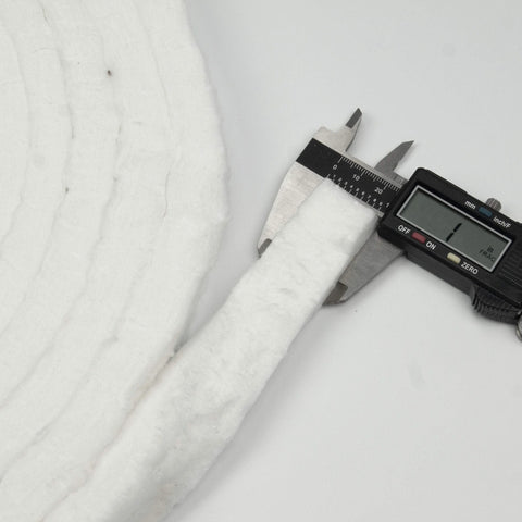 Close-up of white Lynn Manufacturing ceramic fiber strip blanket measured with caliper; 1 in wide, 1/2 in thick
