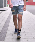 Man walking on street wearing All Day Ankle Stabilizer Brace With Stirrup Support For Foot Injuries Tendonitis And Chronic Ankle Instability