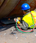 Worker using Oxy Acetylene Torch Hose Twin Cutting 25 Ft By One Quarter Inch B Fitting Welding Gas Hose under large metal structure.